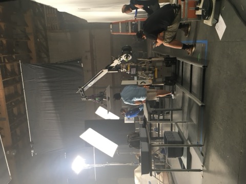 A robotic camera crane and dolly track rigged on a film soundstage, crew reviewing the setup.